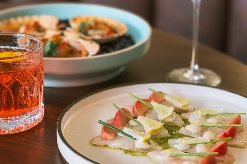 Carpaccio de poisson au citron et radis, avec deux cocktails sur une banquette en cuir