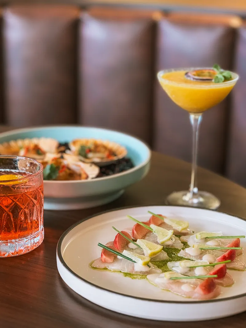 Carpaccio de poisson au citron et radis, avec deux cocktails sur une banquette en cuir