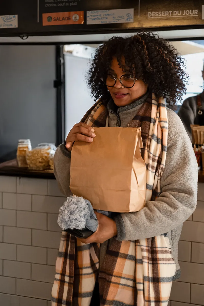 Cliente repartant avec son sac kraft au comptoir de Local Burger Briançon