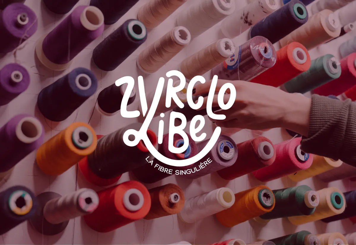 Logo Zyrclo Vibe, la fibre singulière, en blanc sur des bobines de fil colorées