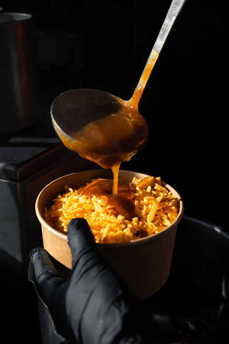 Louche de sauce versée sur du cheddar râpé dans un pot kraft, Local Burger Briançon