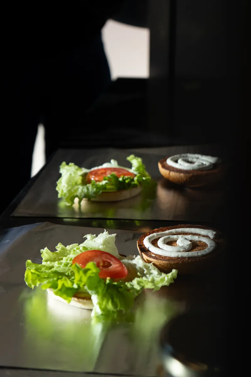Préparation d'un burger : salade, tomate et sauce sur le pain, Local Burger Briançon